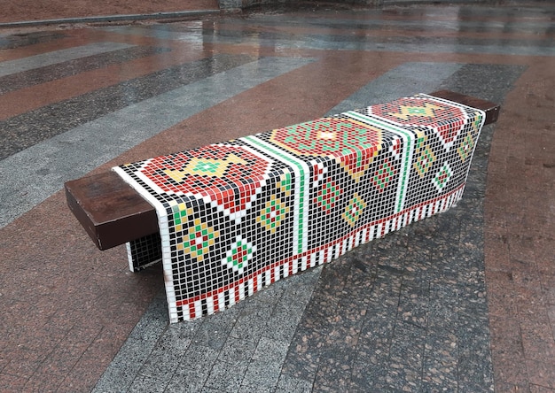 Handmade decorative bench in the form of a lying ornamental towel made of mosaic tiles