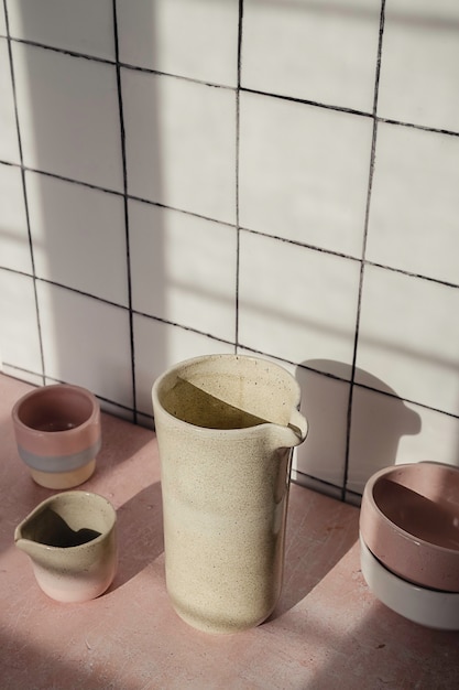 handmade empty tableware such as ceramic jars, mugs and dishes composition on a white kitchen tile.