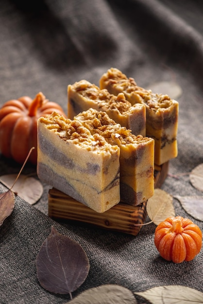 Handmade fragrant natural soap and pumpkin shaped candles on a dark background with yellow dry leaves to create a cozy atmosphere Beautiful autumn postcard