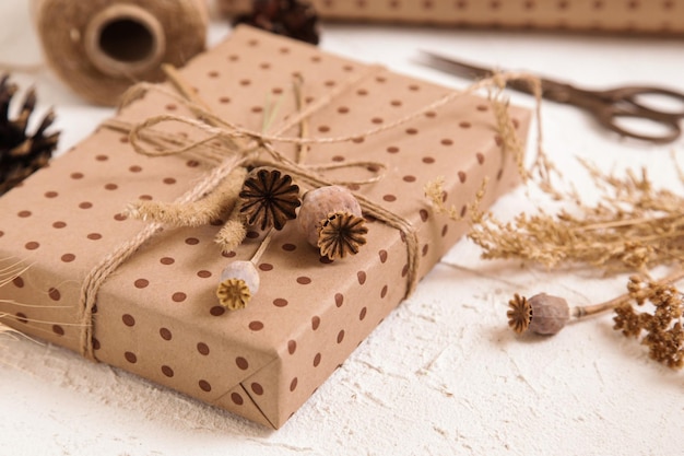 Handmade gift box in craft packaging and dry poppy flowers on white desk Floristic herbarium craft zero waste Natural colours