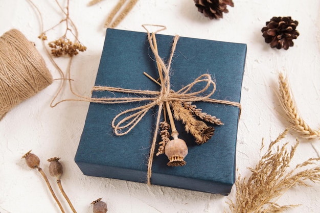 Handmade gift box in dark blue packaging poppy seed heads dried flowers Gift for man Floristic herbarium craft Natural colours copy space