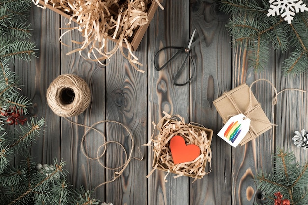 Подарочная коробка ручной работы в праздничной упаковке, украшенная радужной открыткой, вид сверху Еловые ветки, наполнитель и инструменты, концепция рождественского или новогоднего праздника ЛГБТ-символ гомосексуальной ориентации