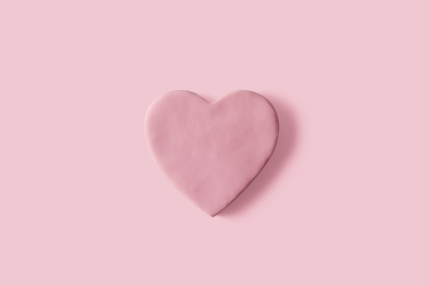 Handmade heart with pink plasticine on pastel background copy space