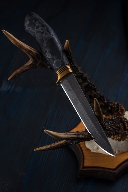 Handmade hunting knife made of Damascus steel lies on the horns