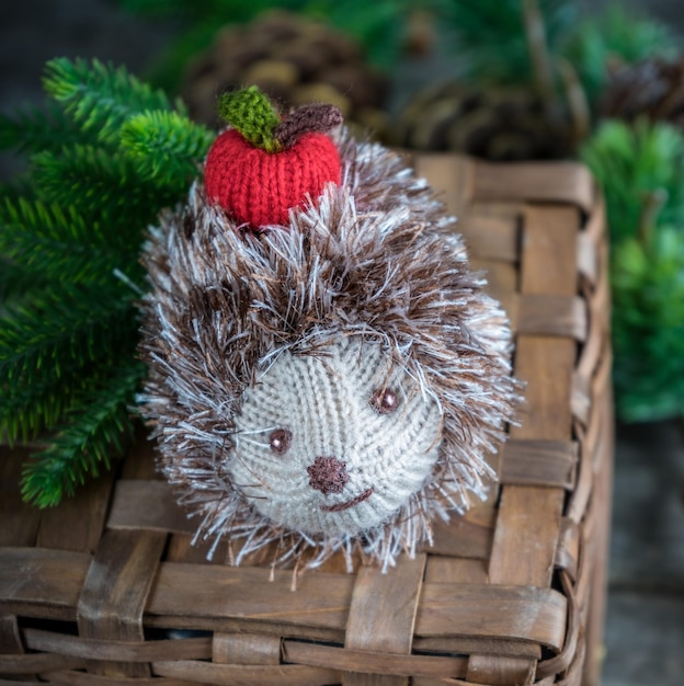 Handmade knitted hedgehog with a red apple on a wicker basket