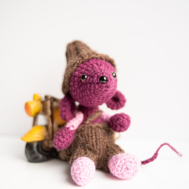 Handmade knitted toy. A rat crocheted with a yellow motorcycle