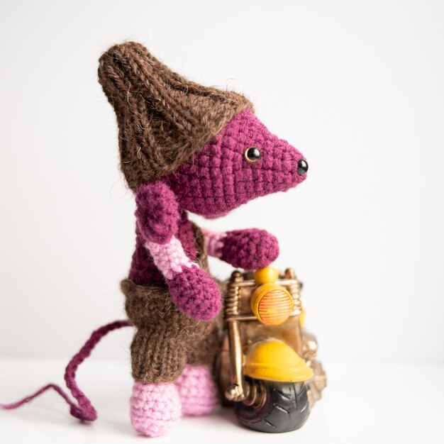 Handmade knitted toy. A rat crocheted with a yellow motorcycle