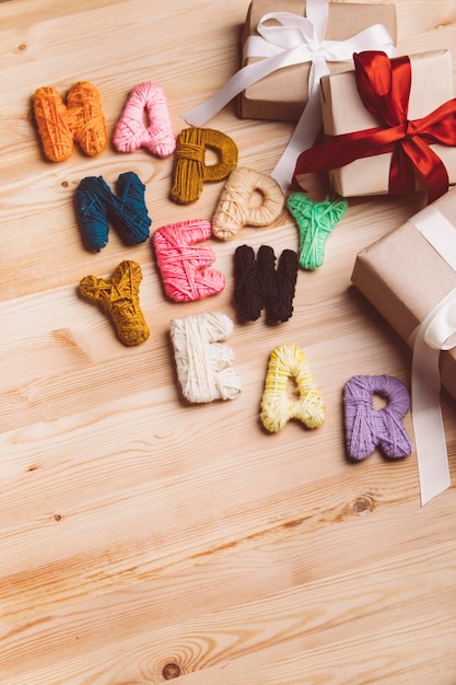 Handmade knitting letters with Happy new year wish gift boxes on table