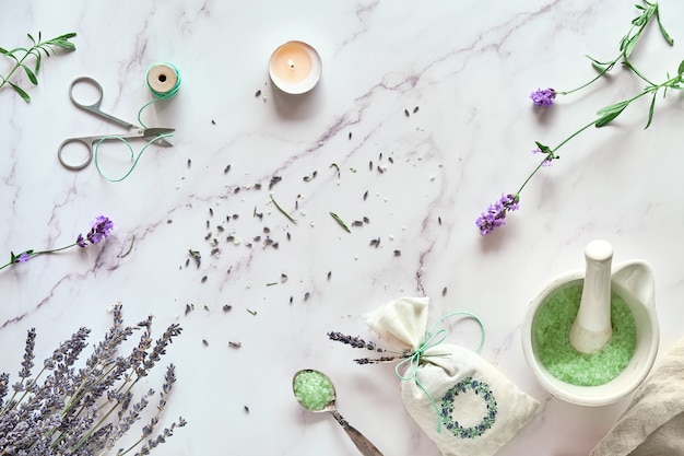 Handmade lavender sachets and homemade bath salt. Lavender flowers, both fresh and dry. Flat lay on light marble