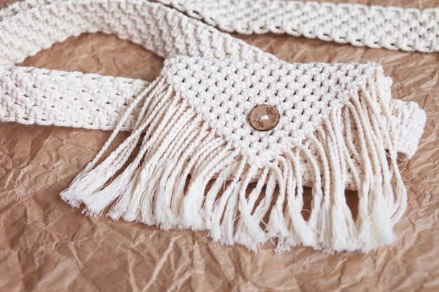 Handmade macrame belt bag on craft paper background ECO friendly natural macrame cotton waist bag Hobby knitting handmade macrame Modern summer concept