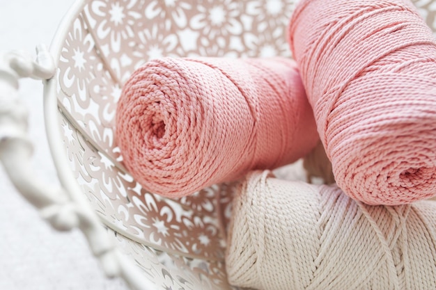 白い背景のバスケットに手作りのマクラメ編みと綿糸