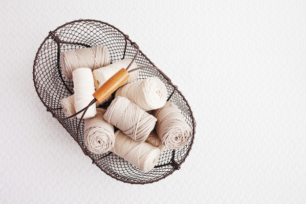 Handmade macrame braiding and cotton threads in basket