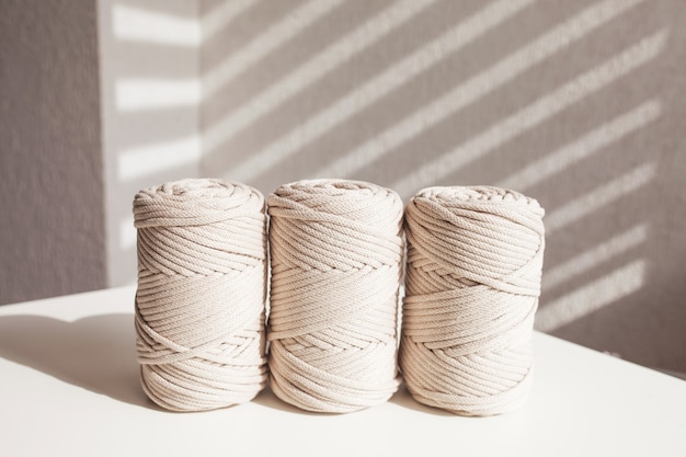 handmade macrame braiding and natural cotton threads stack on a white background with shadows