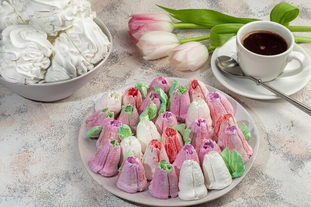 Handmade marshmallows on a light background in the form of roses, hydrangeas and tulips. There are flowers nearby. Women's day, Valentine's day.