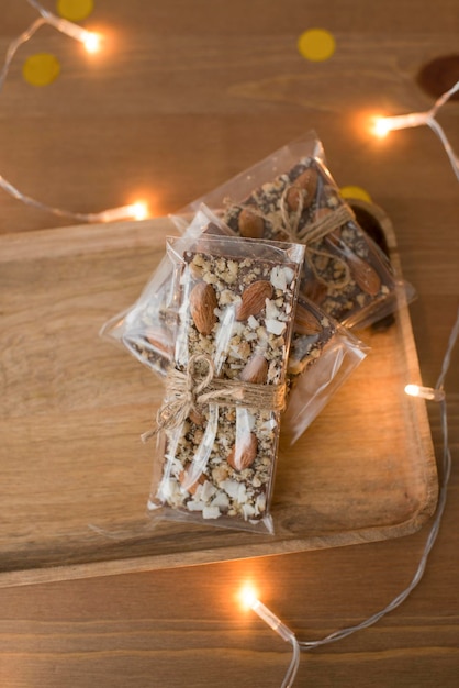 Handmade milk chocolate with nuts in a package on a wooden background