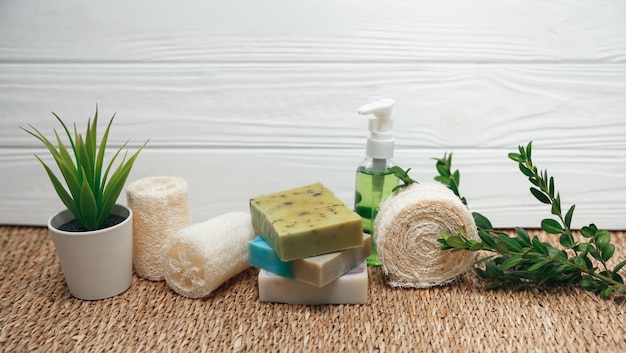 Handmade natural soap, facial brush, terry towels, loofah sponge with green plant. Healthy lifestyle concept. Beauty, skin care. Set of bath and spa accessories.