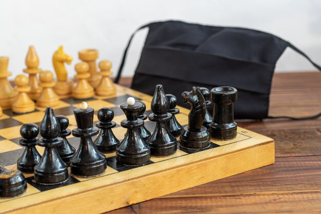 Handmade old chess on a wooden board. Occupation on vacation and quarantine. The concept of isolation.