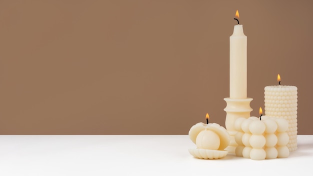 Handmade olive wax different forms burning candle on a duotone\
brown and white background sustainability vegan candle natural\
materials minimalistic cozy atmosphere modern photo copy\
spacebanner