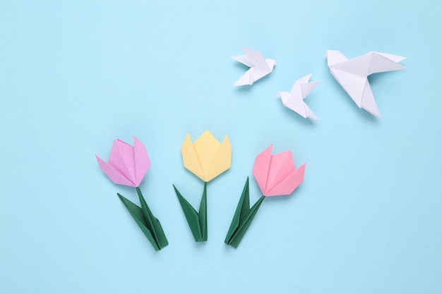 Handmade origami paper tulips and pigeonsxAon blue background 8 March mother's day or easter concept Top view Minimalism