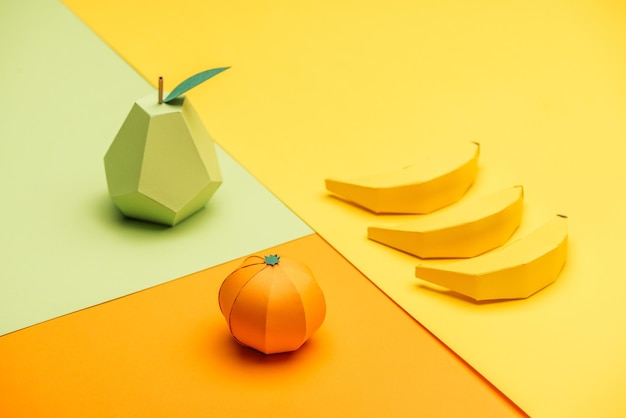 Handmade origami pear bananas and tangerine on colorful paper