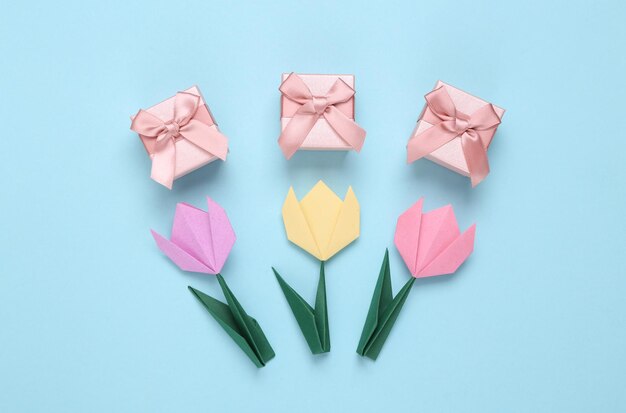 Tulipani origami fatti a mano e scatole regalo su sfondo blu concetto di festa della donna dell'8 marzo vista dall'alto minimalismo