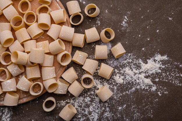 Handmade pasta on a brown background is the subject of this photo The noodles are various shapes and