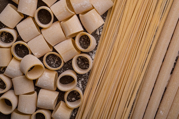 Handmade pasta on a brown background is the subject of this photo The noodles are various shapes and