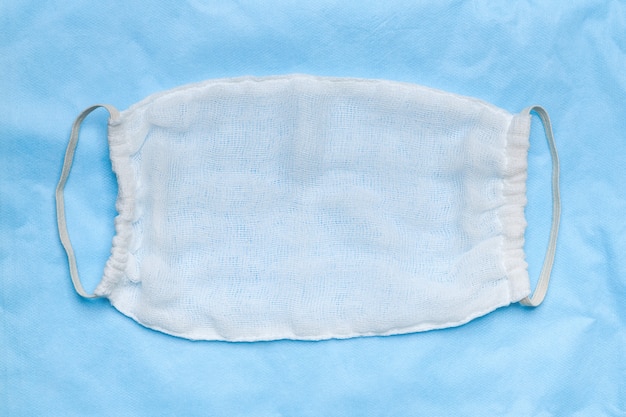 handmade protective surgical face mask made from white sterile cheesecloth blue medical background