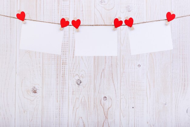 Handmade red felt hearts and white paper hanging on a rope with clothespins