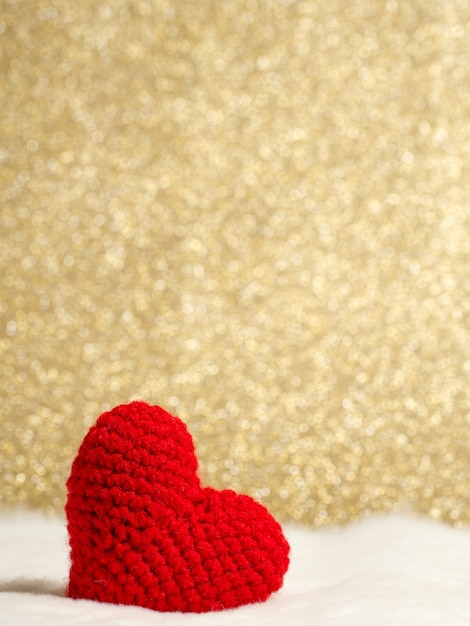 handmade red yarn heart on white wool and golden background copy space for text.