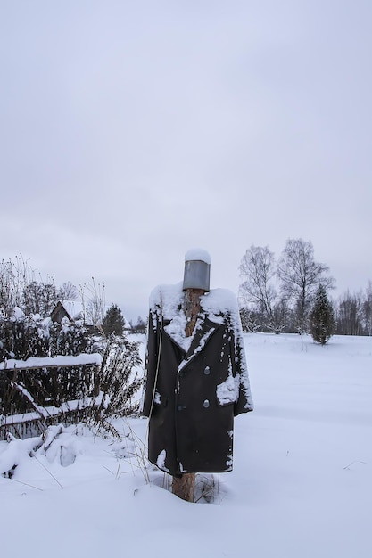 Handmade scarecrow on a snowy field in the village at winter.