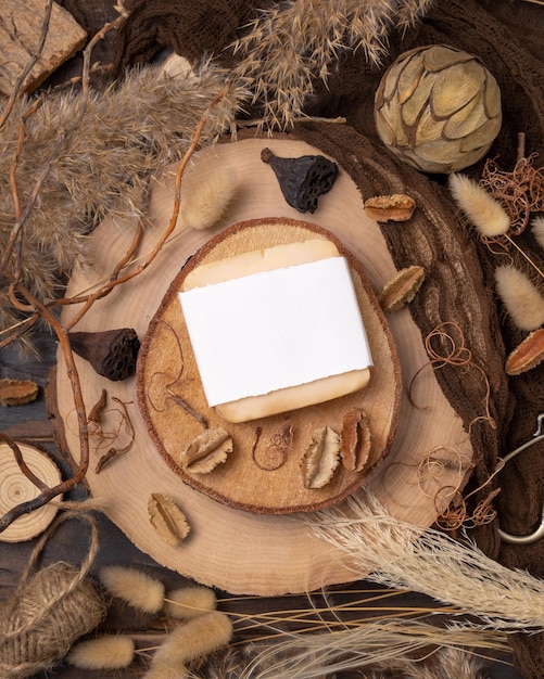 Мыло ручной работы с пустой этикеткой на дереве рядом с натуральными украшениями, вид сверху