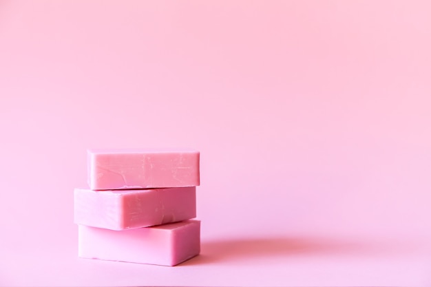 Handmade soap bars on soft pink background.