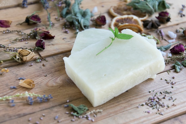 Handmade soap bars with herbs on  wooden table, soft focus