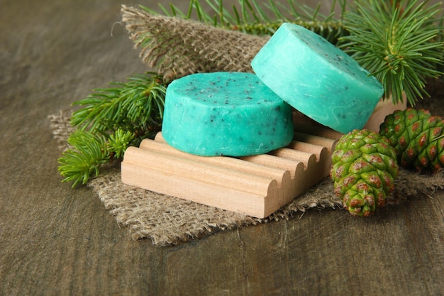 Handmade soap and green pine cones on wooden background