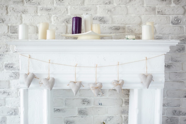 Photo handmade textile white hearts hanging on a cord on white brick wall