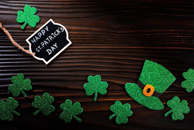 Handmade threeleaved shamrock greeting label and ivy hat on wooden background