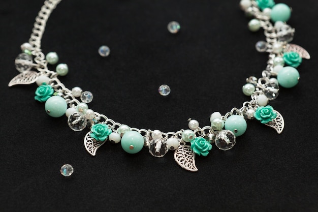 Photo handmade turquoise necklace, shiny crystals gemstone beads plastic flowers metallic leaves top view