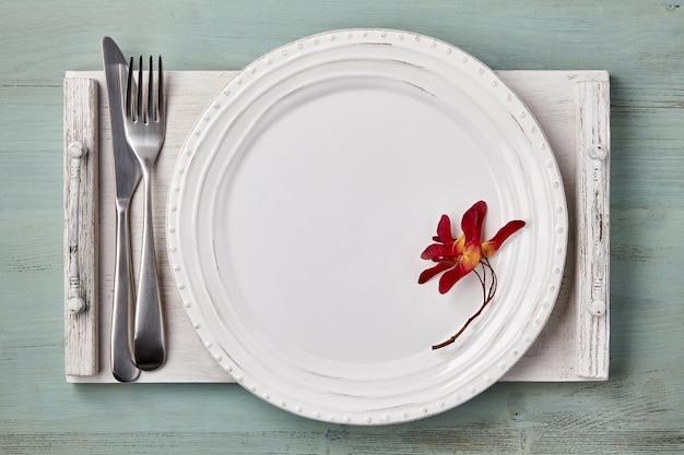 Handmade white ceramic plate with maple spouts and cutlery on a white wooden tray. Mockup for displaying dishes