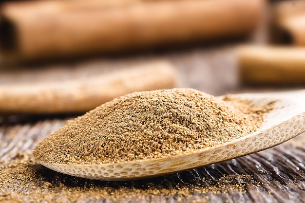 Handmade wooden spoon with cinnamon powder on brown wooden table food closeup food condiment powder macro photography