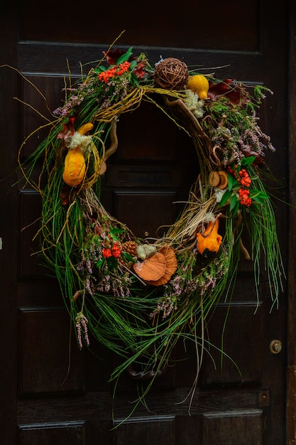 Handmade wreath of zucchini mushrooms cones hanging on a brown vintage door