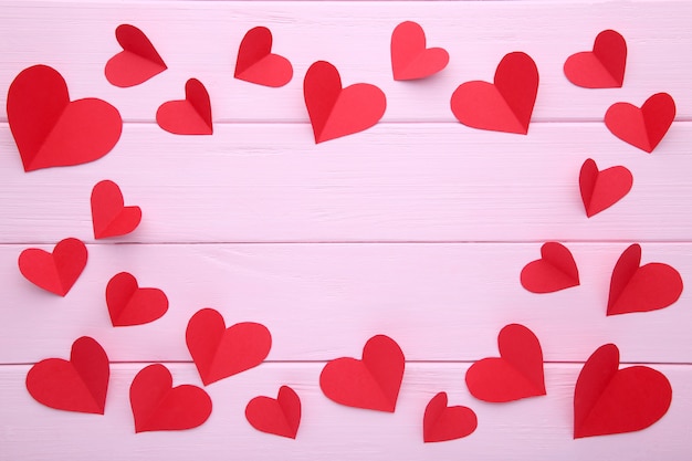 Handmaded red hearts on pink background.