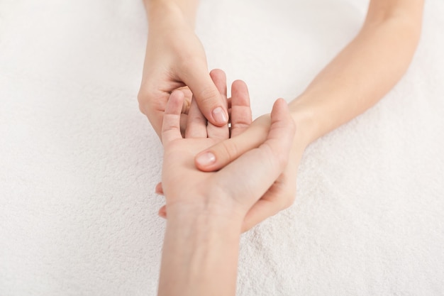 Handmassage. Fysiotherapeut drukt op specifieke plekken op vrouwelijke handpalm. Professionele gezondheids- en welzijnsacupressuurmanipulaties, kopieerruimte, close-up