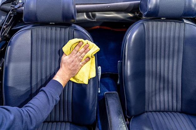 Handmatige reiniging van het leer in het interieur van de auto met een microhanddoek