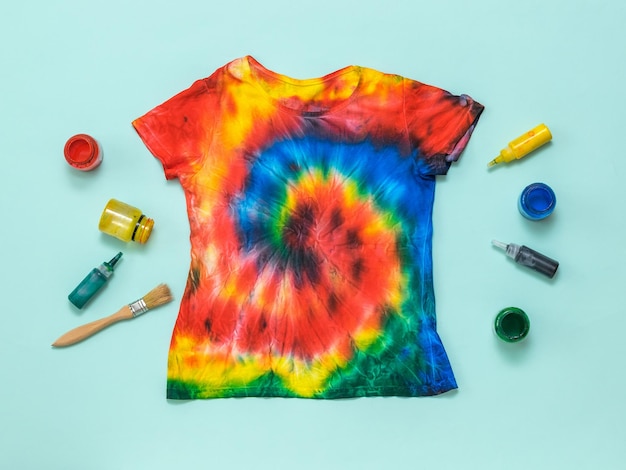 Handpainted tshirt in tie dye style and paint on a light blue background Flat lay