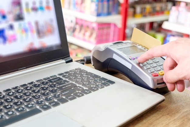 Handpers met creditcard op termimal en met behulp van laptopbetaling online winkelen