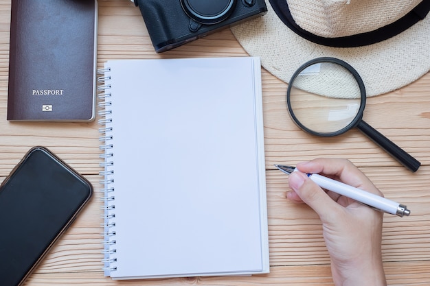 Handreiziger die op notitieboekje met toebehoren, Camera, Paspoort schrijven