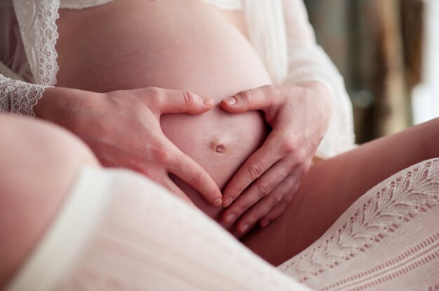 Mani sull'addome di una donna incinta. cuore.