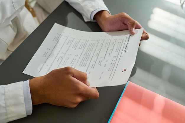 Photo hands of african american teenage guy holding paper with exam test