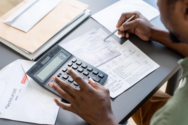 Hands of african man pressing buttons of calculator